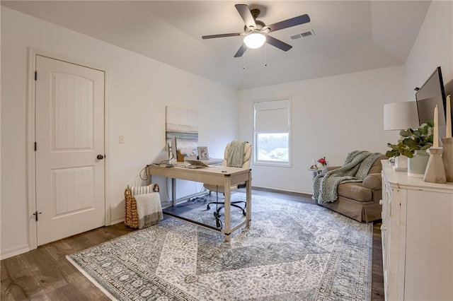 office space featuring dark hardwood / wood-style flooring, a tray ceiling, and ceiling fan