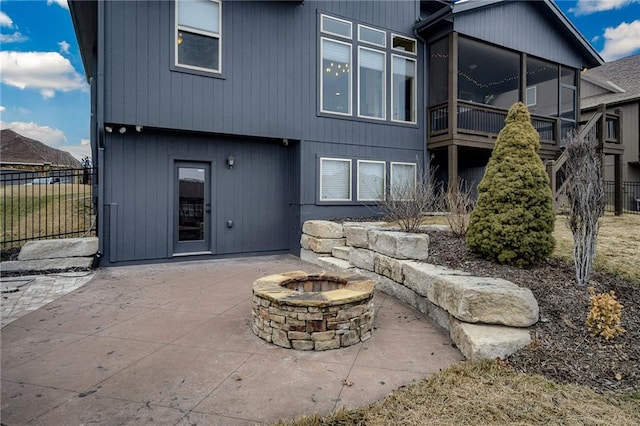 rear view of property with a fire pit, a patio area, and a sunroom