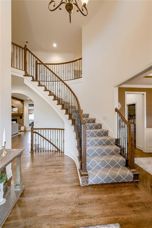 stairs featuring hardwood / wood-style flooring, ornamental molding, a chandelier, and a high ceiling