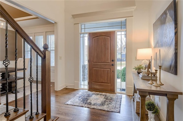 foyer with ornamental molding and dark hardwood / wood-style flooring