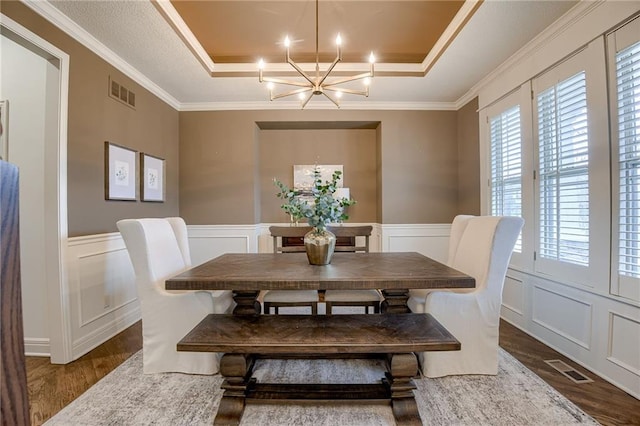 dining area featuring ornamental molding, dark hardwood / wood-style floors, an inviting chandelier, and a tray ceiling