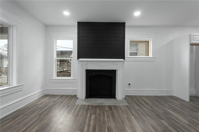 unfurnished living room featuring a healthy amount of sunlight, dark hardwood / wood-style flooring, and a fireplace