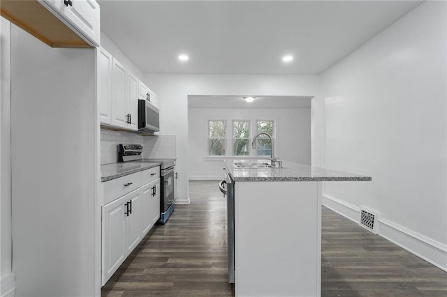 kitchen with white cabinets, appliances with stainless steel finishes, light stone countertops, and sink