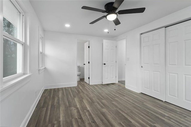 unfurnished bedroom with ceiling fan, dark hardwood / wood-style flooring, connected bathroom, and a closet