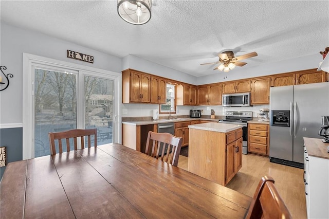 kitchen featuring ceiling fan, sink, a center island, a textured ceiling, and appliances with stainless steel finishes