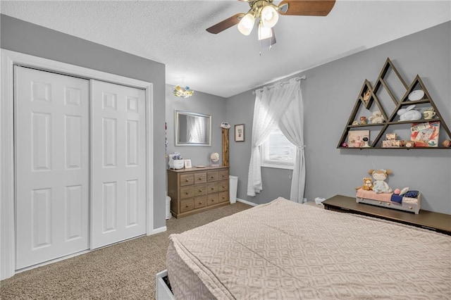 bedroom with a textured ceiling, ceiling fan, light carpet, and a closet