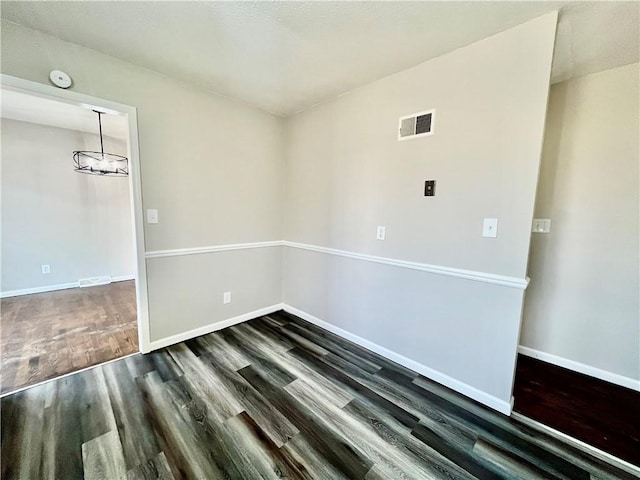 empty room featuring dark hardwood / wood-style flooring and an inviting chandelier