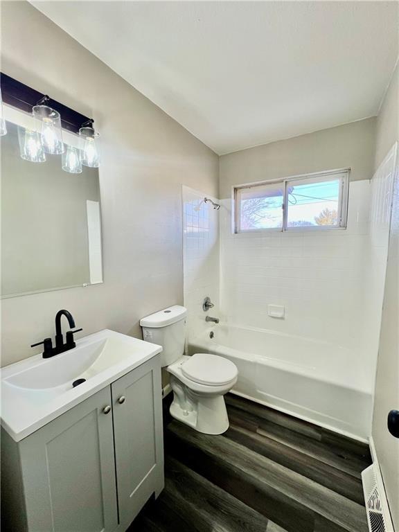 full bathroom featuring toilet, hardwood / wood-style floors, vanity, and tiled shower / bath