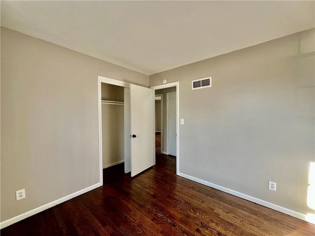 unfurnished bedroom with a closet and dark wood-type flooring