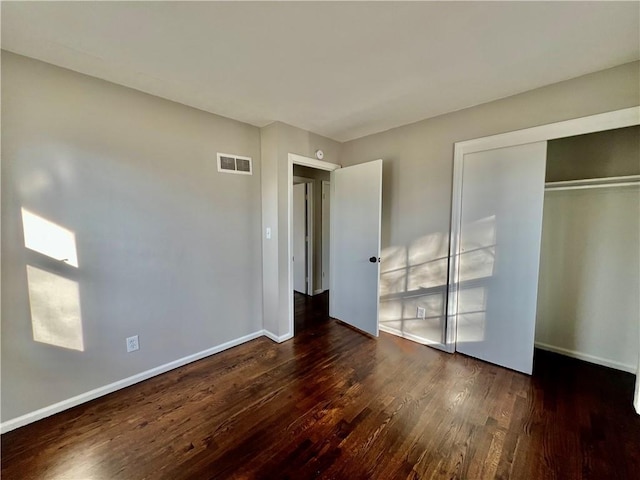 unfurnished bedroom with dark hardwood / wood-style floors and a closet