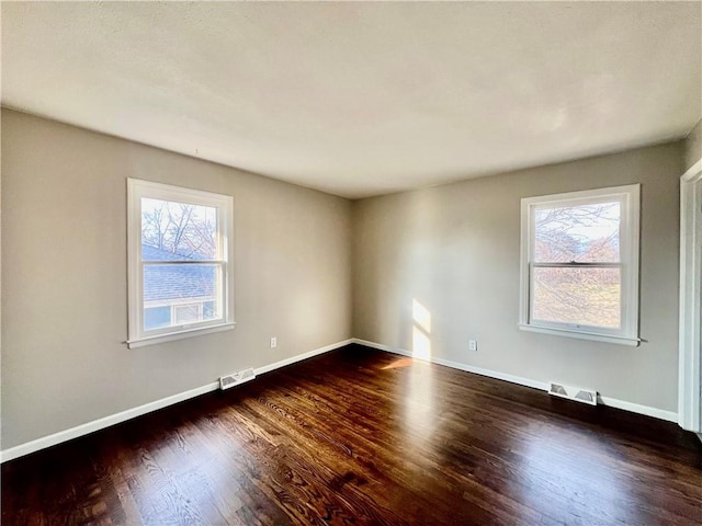 spare room with plenty of natural light and dark hardwood / wood-style floors