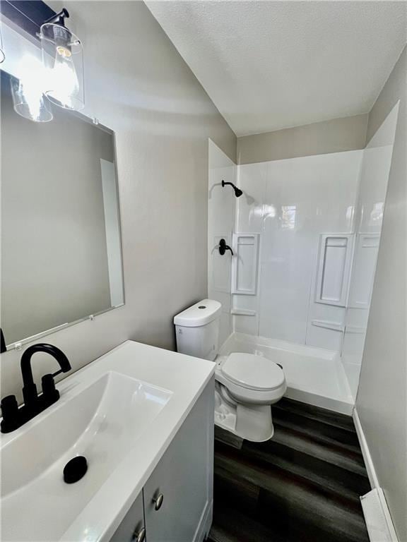 bathroom with hardwood / wood-style flooring, vanity, toilet, and a shower