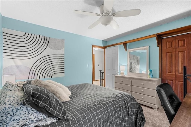 bedroom featuring ceiling fan, light colored carpet, and a textured ceiling