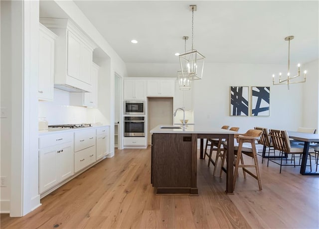 4218 W 158th Ter, Overland Park, KS 66224 - kitchen featuring a chandelier, appliances with stainless steel finishes, light wood-type flooring, an island with sink, and recessed lighting