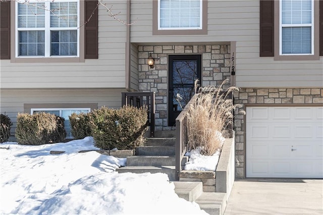 snow covered property entrance with a garage