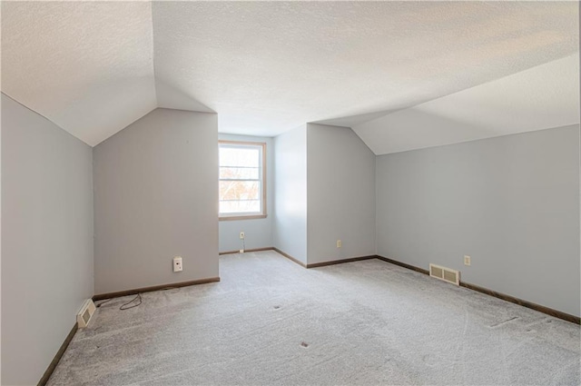 bonus room featuring a textured ceiling, light carpet, and lofted ceiling