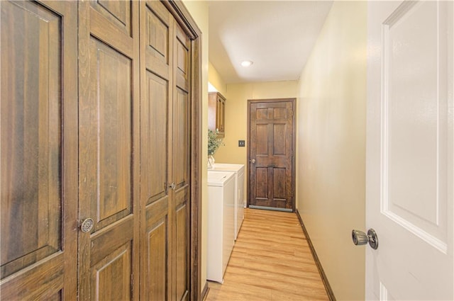 clothes washing area featuring washer and clothes dryer, cabinets, and light hardwood / wood-style flooring