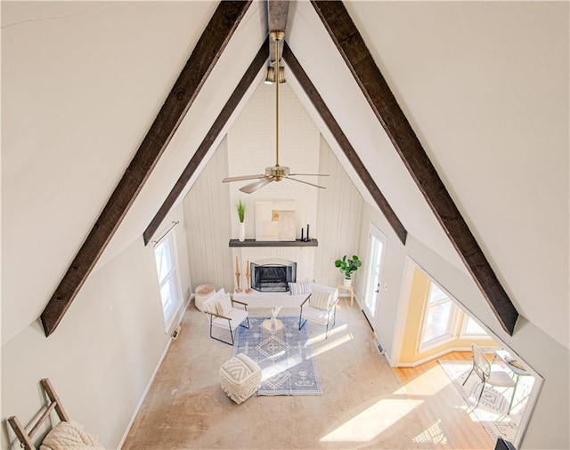 carpeted living room featuring a fireplace, ceiling fan, beamed ceiling, and wooden walls