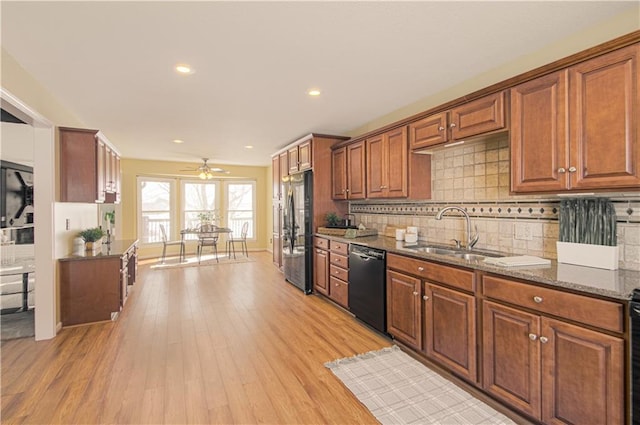 kitchen with dishwasher, light hardwood / wood-style floors, dark stone counters, stainless steel fridge, and sink