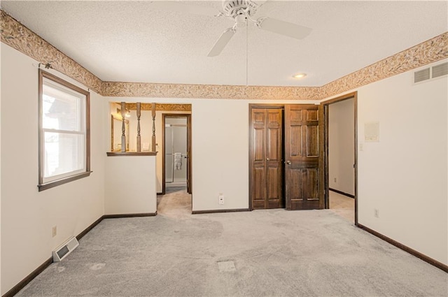 unfurnished bedroom with light colored carpet, ceiling fan, and a textured ceiling