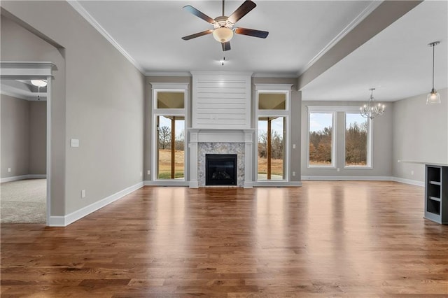 unfurnished living room featuring hardwood / wood-style floors, ceiling fan with notable chandelier, ornamental molding, and a premium fireplace