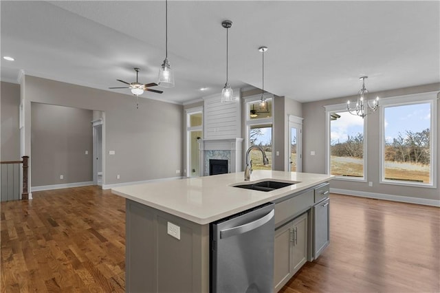 kitchen with pendant lighting, dishwasher, a kitchen island with sink, sink, and gray cabinets