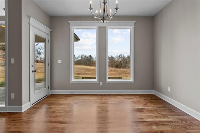 unfurnished dining area with a chandelier and wood-type flooring