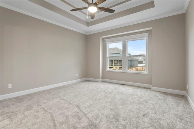 unfurnished room with ceiling fan, a raised ceiling, light colored carpet, and crown molding