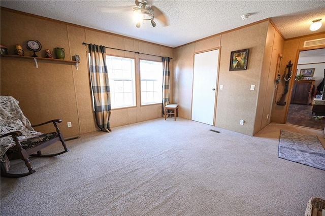 sitting room with ceiling fan, carpet floors, and a textured ceiling