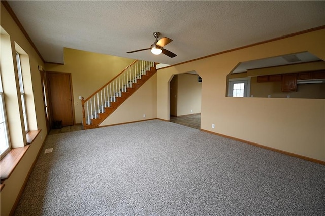 empty room with dark colored carpet, a textured ceiling, ceiling fan, and ornamental molding