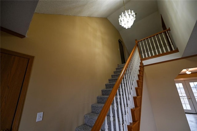 staircase featuring french doors, high vaulted ceiling, and a notable chandelier