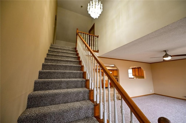 stairs featuring carpet flooring, a textured ceiling, and ceiling fan with notable chandelier