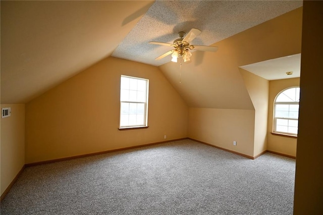 additional living space featuring carpet, a textured ceiling, vaulted ceiling, and ceiling fan