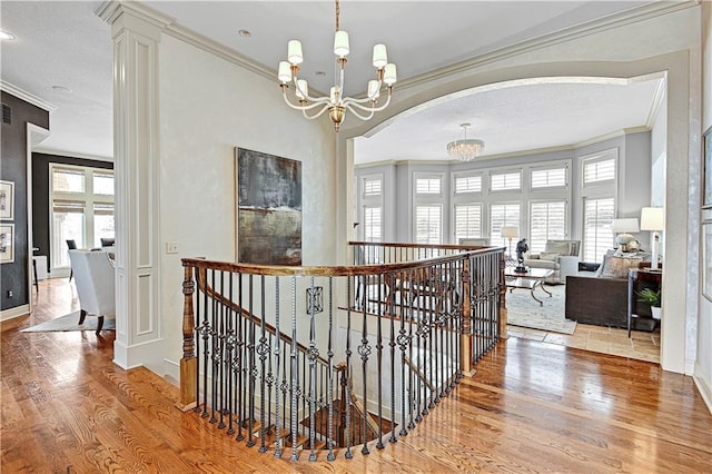 hallway featuring crown molding, wood-type flooring, and a notable chandelier