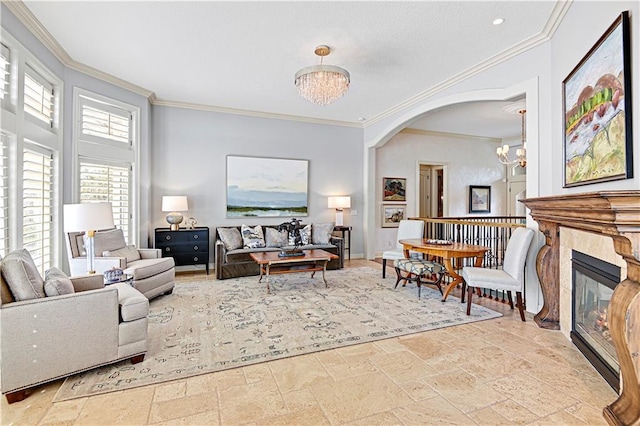 living room featuring a tile fireplace, crown molding, and a chandelier