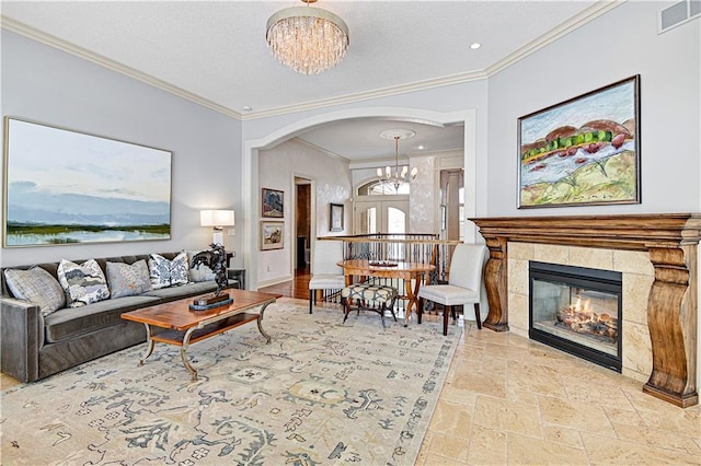 living room featuring crown molding, a tiled fireplace, and a notable chandelier