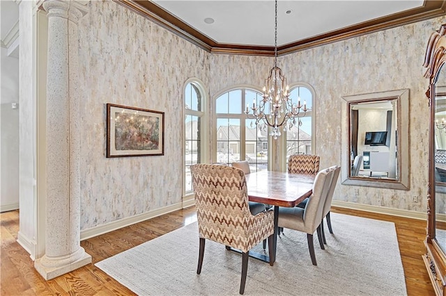 dining area featuring crown molding, light hardwood / wood-style flooring, a chandelier, and ornate columns