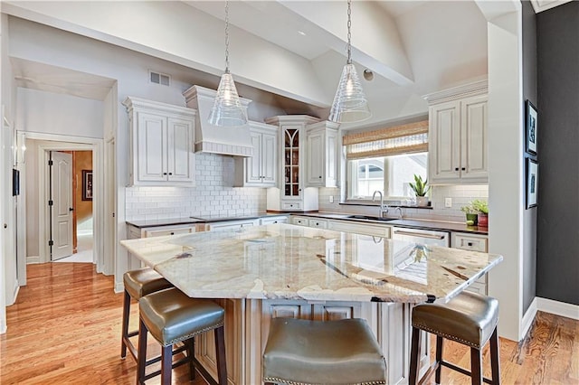 kitchen with a breakfast bar, pendant lighting, sink, dark stone countertops, and a spacious island