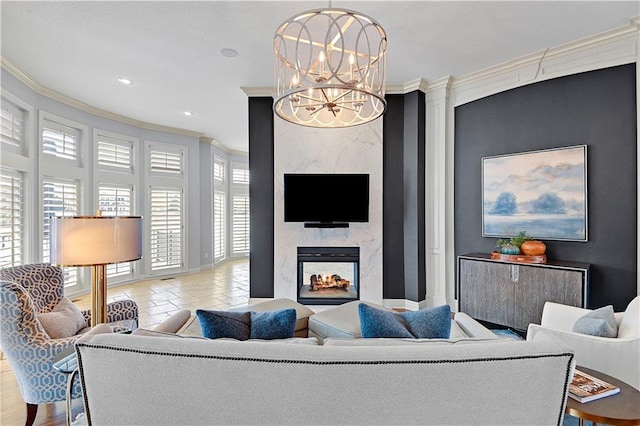 living room with ornamental molding, a notable chandelier, and a high end fireplace