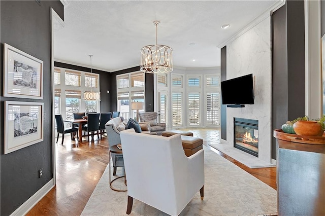 living room featuring an inviting chandelier, crown molding, light hardwood / wood-style floors, and a large fireplace