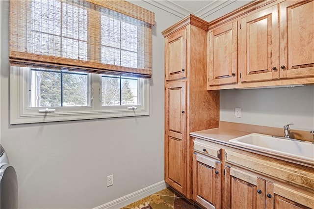 kitchen with crown molding, sink, and dark tile patterned floors