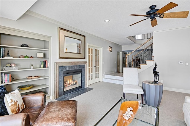 living room with carpet flooring, ornamental molding, ceiling fan, a textured ceiling, and built in shelves