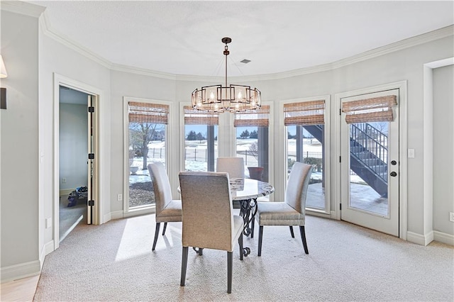 dining area with crown molding, light colored carpet, and a chandelier