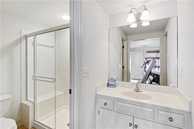 bathroom featuring an enclosed shower, vanity, a textured ceiling, and toilet