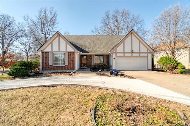 tudor house with concrete driveway, an attached garage, brick siding, and roof with shingles