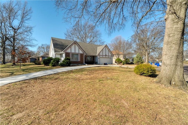 tudor home featuring driveway, an attached garage, a shingled roof, a front lawn, and brick siding