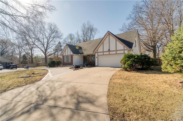 english style home with board and batten siding, fence, a front yard, driveway, and an attached garage