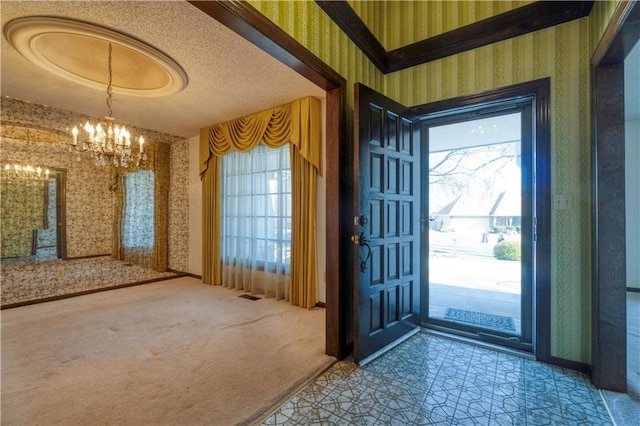 foyer entrance with wallpapered walls, a textured ceiling, carpet, and a chandelier