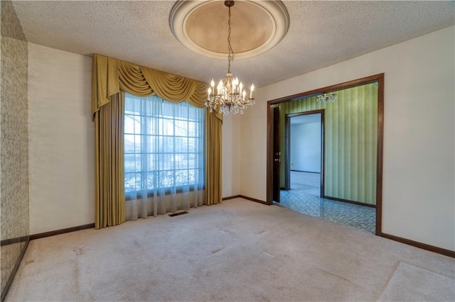 carpeted spare room featuring baseboards, a chandelier, and a textured ceiling