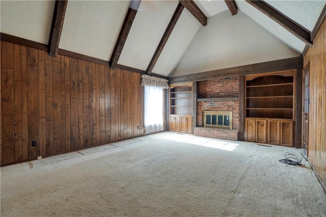 unfurnished living room with beam ceiling, wood walls, a fireplace, and carpet floors